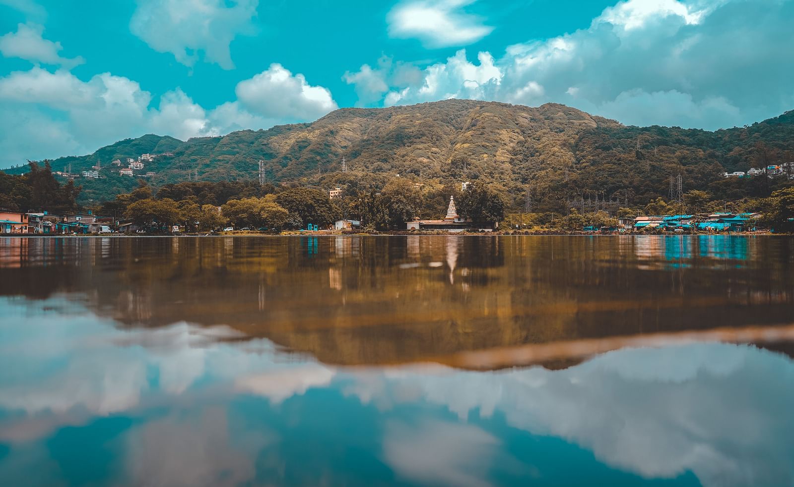 Landscape view of hills with a lake in front and the reflection of the sky on it
