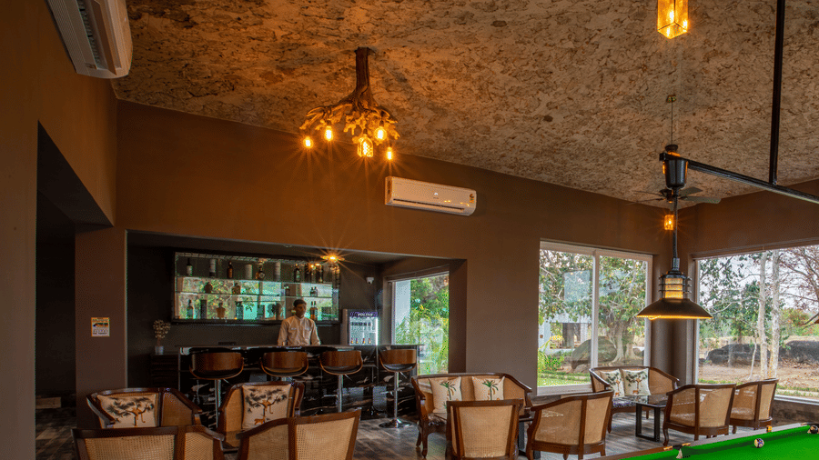 Snooker table and a bar which features several sets of table and chairs at The Riverwood Forest Retreat, Kanha.