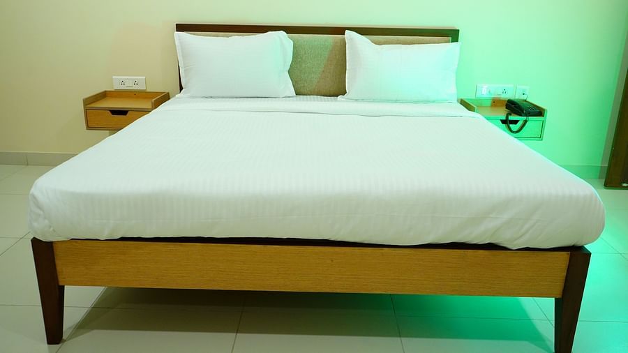 An image of a tidy bed with two side drawers and a dial phone - A M Suites