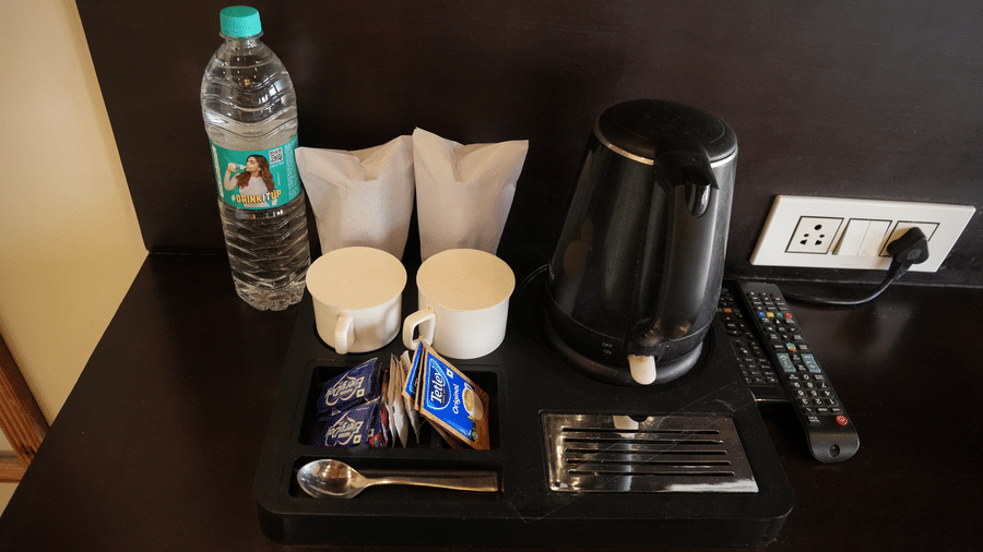 A bunch of sachets for tea and coffee, a water bottle, an electric kettle | Sol Glow Resort, Nainital