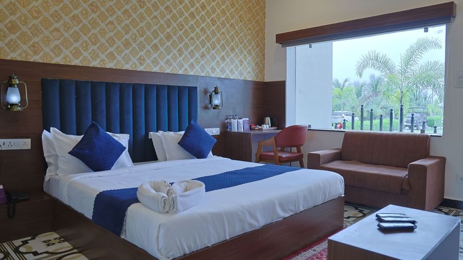A hotel room at VITS Select Diamond Resort, Sasan Gir, with a bed, desk, and a window overlooking a lush garden.