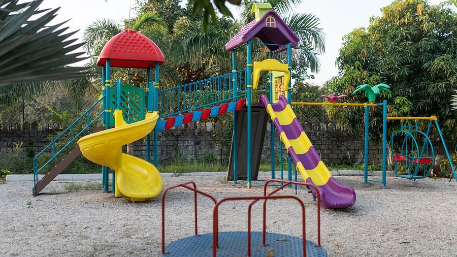 A playground with 2 slides, a merry-go-round, and a ball swing