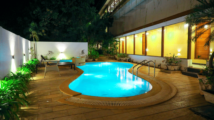 An overview of the swimming pool with lights on in the night - Rosetum Anjuna.