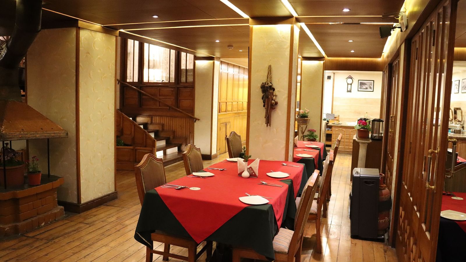 Dining area at Cedar Inn, Darjeeling, featuring spacious seating arrangements, neatly placed cutlery, overhead lighting and a CCTV.