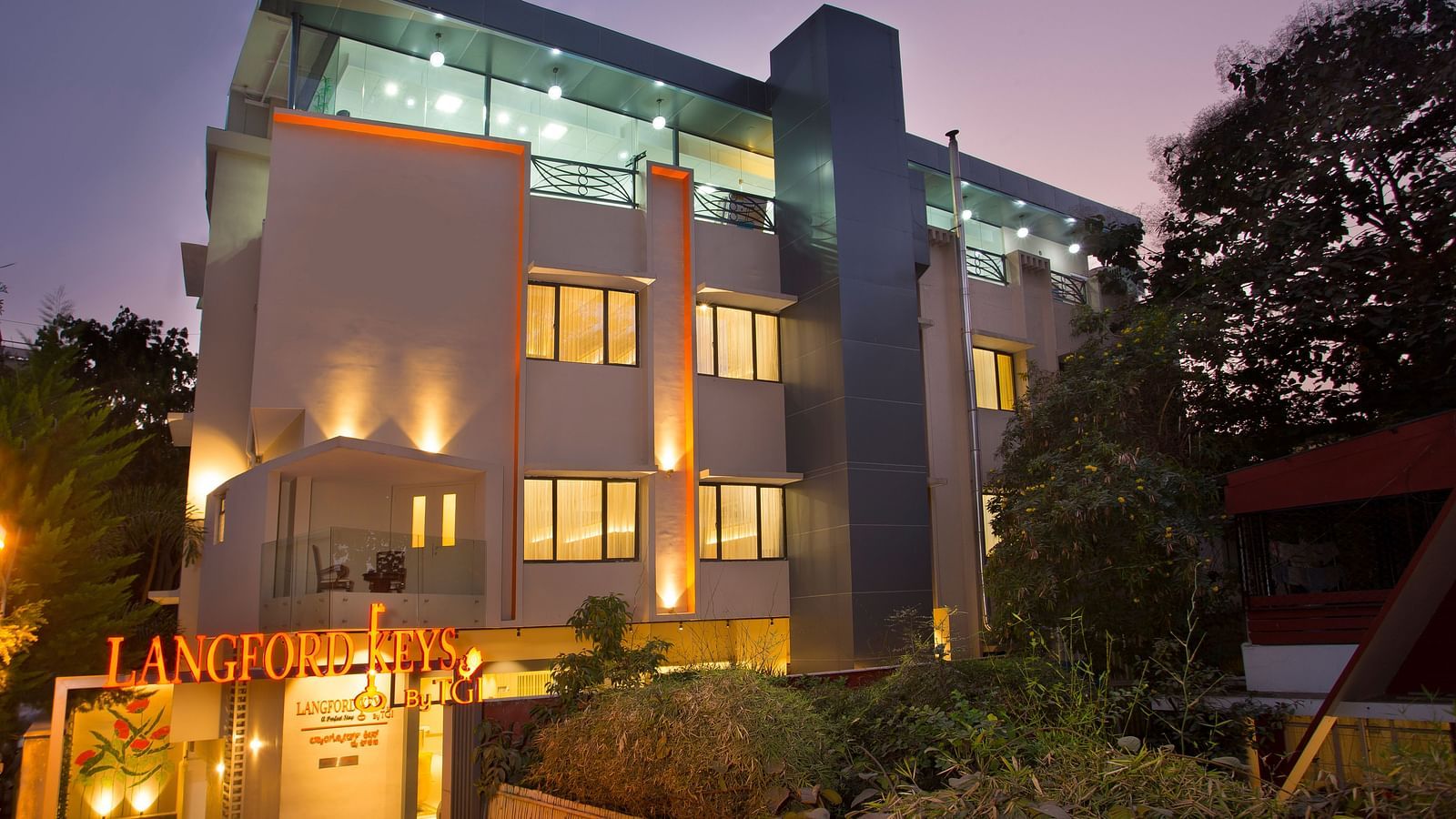 The exterior entrance of Langford Keys Hotel showing the signboard with reflective windows and modern architecture at dusk - Hotel Langford Keys by TGI, Shanti Nagar
