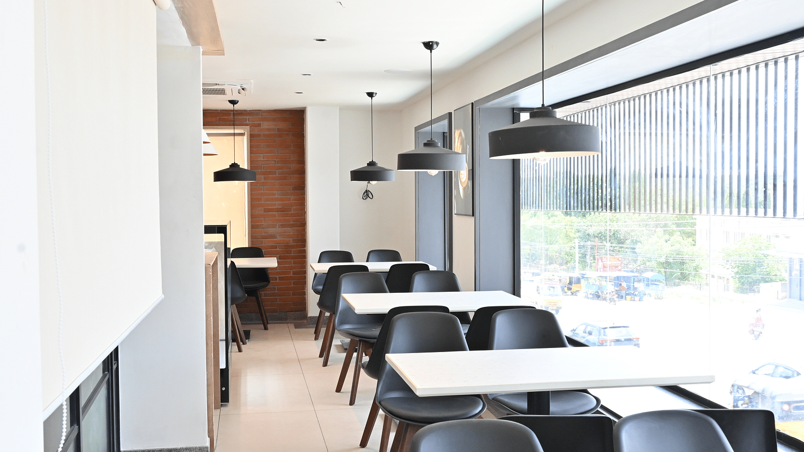 Image of coffee shop with chairs and lights hanging from the ceiling at Hotel Raai