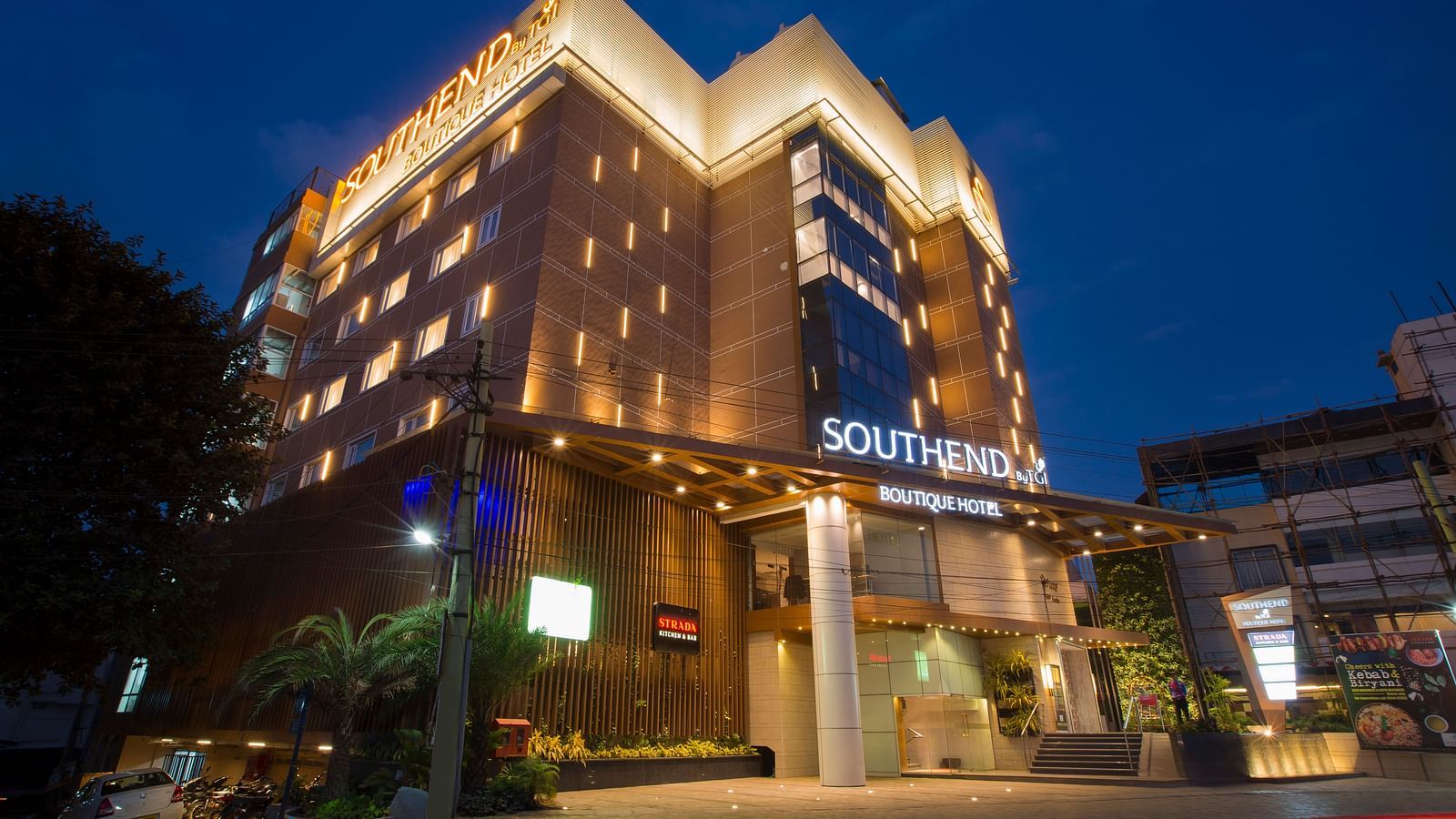 A twilight view of the illuminated facade of the Southend Hotel, with a dark blue sky in the background - Hotel Southend by TGI - Bommasandra, Bangalore