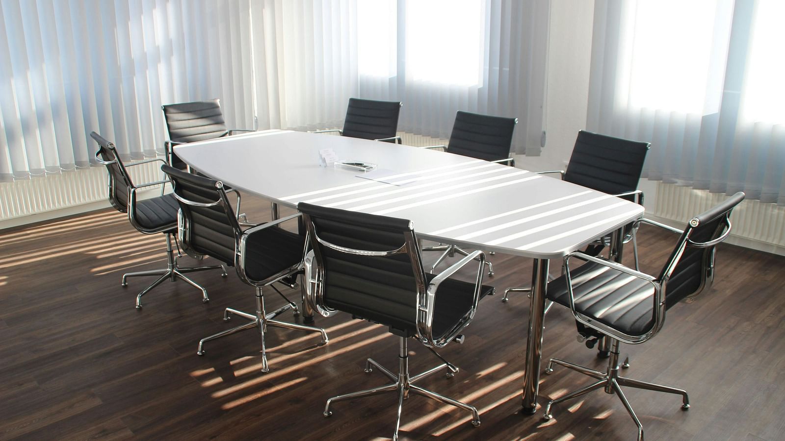 A well-appointed Boardroom featuring a broad table with chairs neatly arranged around it, offering a professional setting for meetings