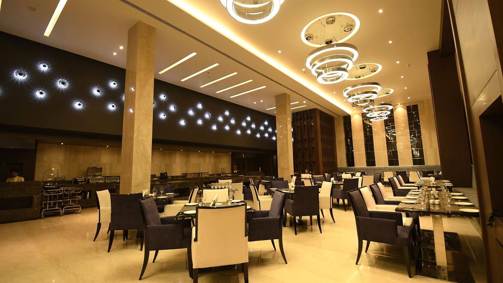 A dining area with warm lighting, where tables are set and chairs are arranged for guests to enjoy their meal