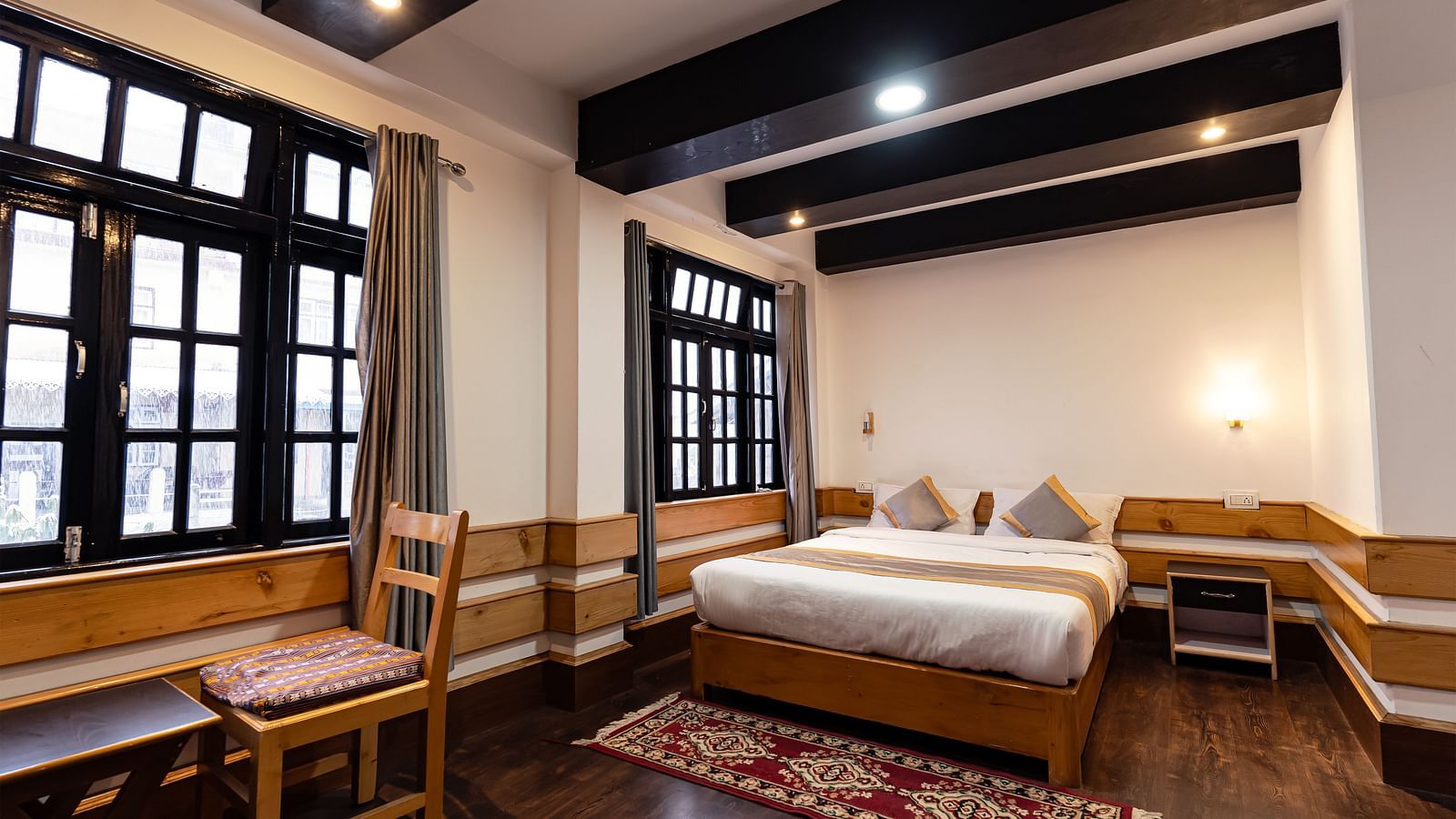 view of the deluxe room with a large bed and a chair with a window in the background at Mystique Valley Resort  