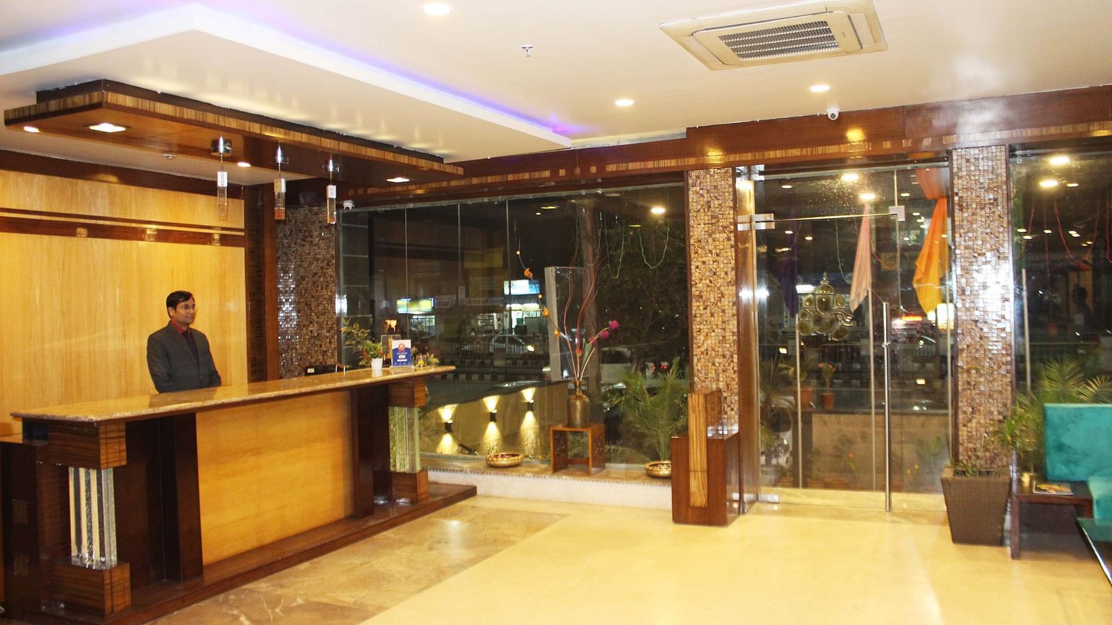 A well lit reception hall with warm yellow lights illuminating the hall and a receptionist to assist the guests  - TGI Apple Inn, Jaipur 