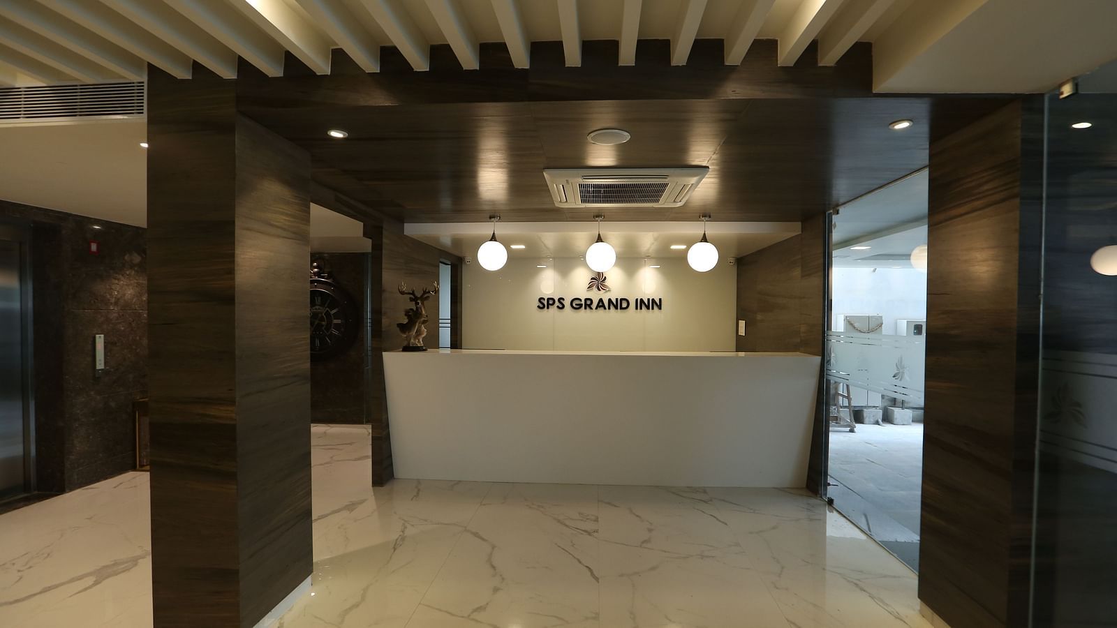 A hotel reception area with a clean, modern design, featuring a front desk and waiting space - TGI SPS Grand, Coimbatore