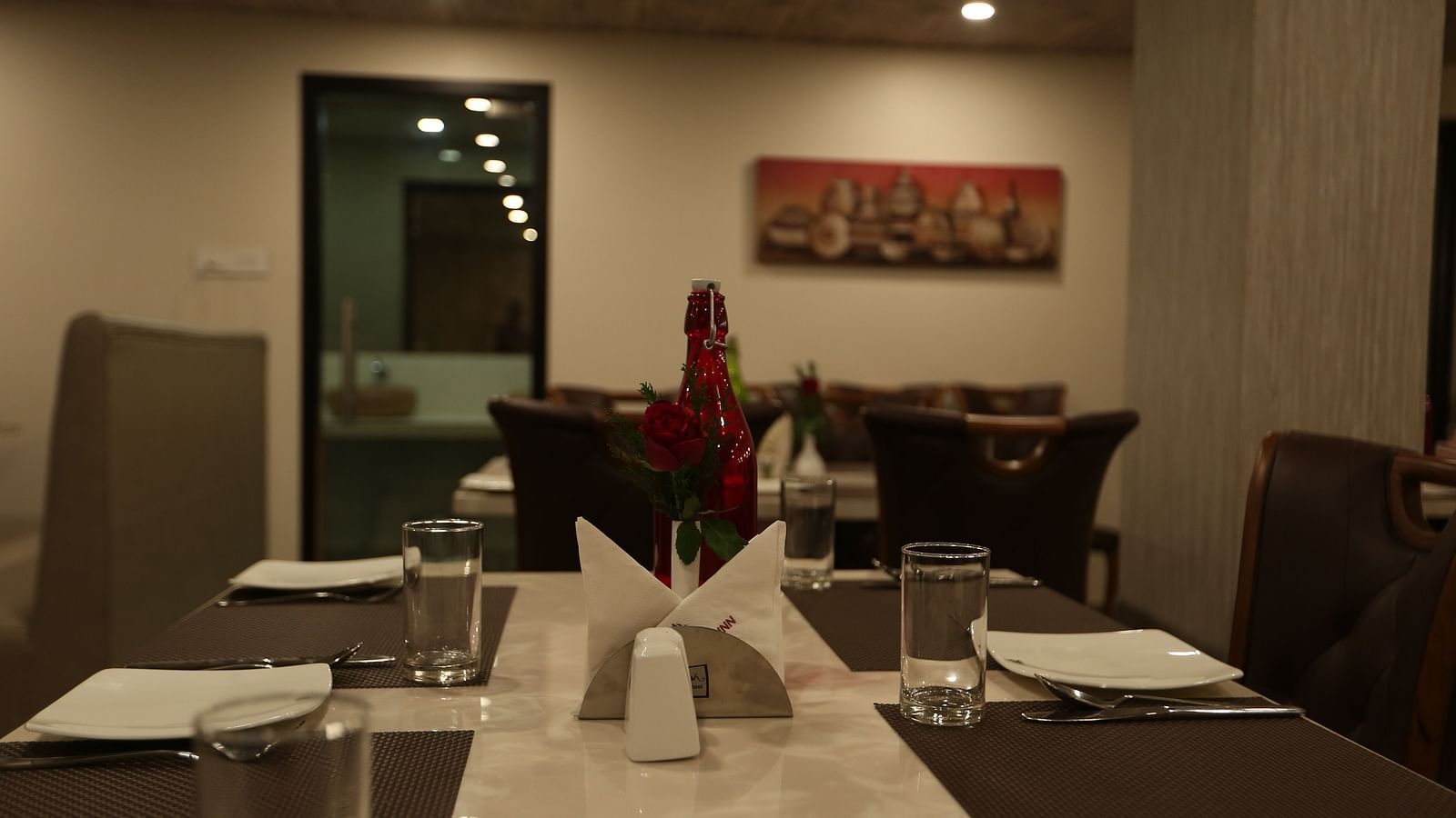 A well-lit restaurant area with dark wood furniture and table settings  - TGI SPS Grand, Coimbatore