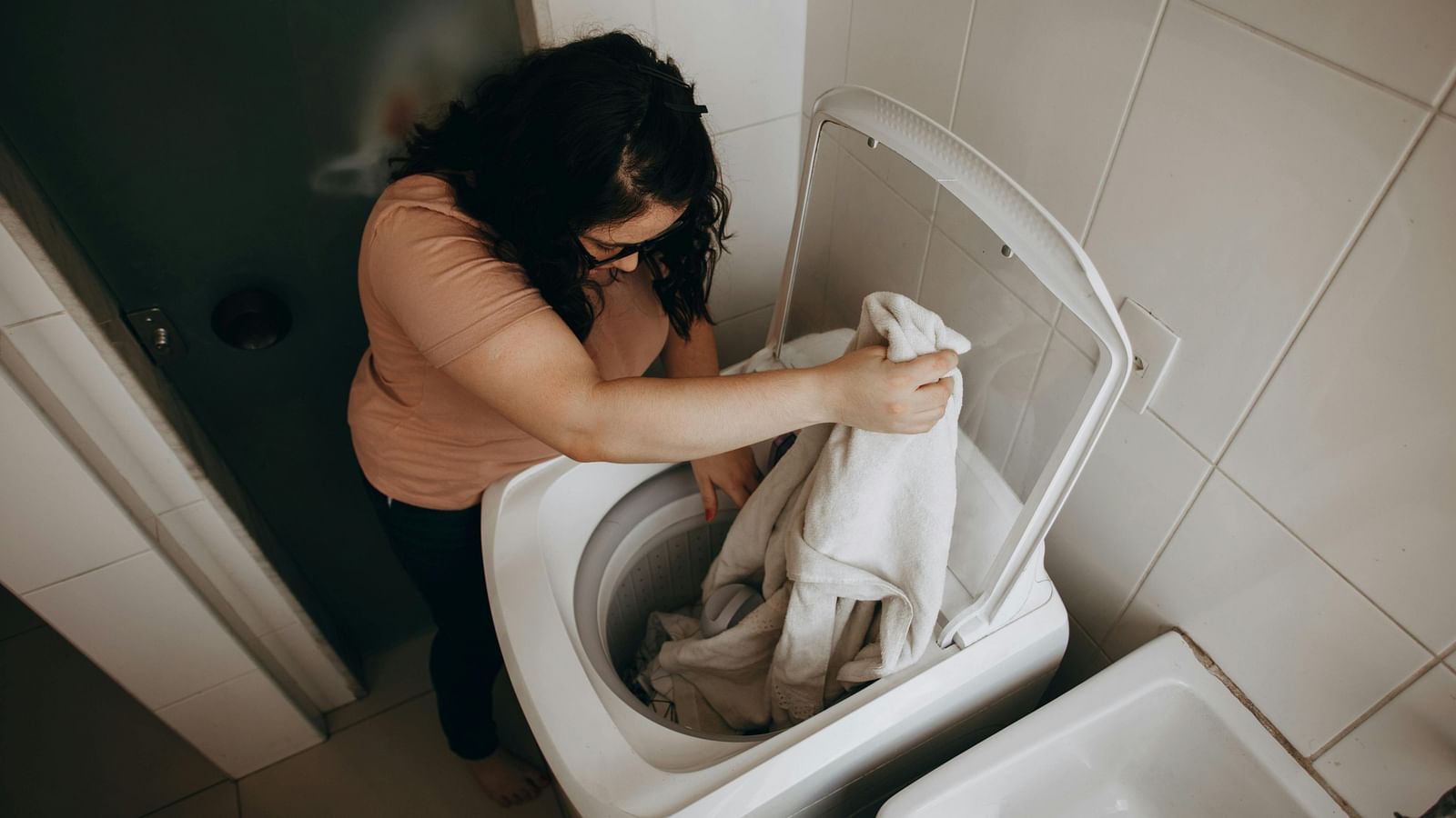 A woman putting her clothes in the washing machine for laundry