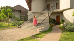 A woman in a pink dress walking up the stairs to a modern villa surrounded by greenery at Ananta Spa and Resort, Ajabgarh.