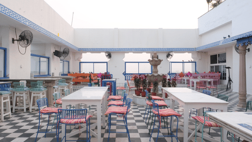 Open-air courtyard dining area featuring colourful seating, tiled flooring, a central fountain, and casual dining spaces designed for relaxed gatherings | Clarks Amer, Jaipur