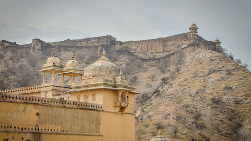The facade of the Jaigarh Fort perched atop a mountain range with rustic brown walls viewed from Amer Fort in Jaipur.