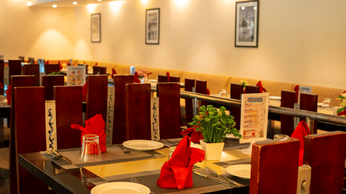 Image of restaurant featuring sets of dining chairs and  tables organised with cutlery