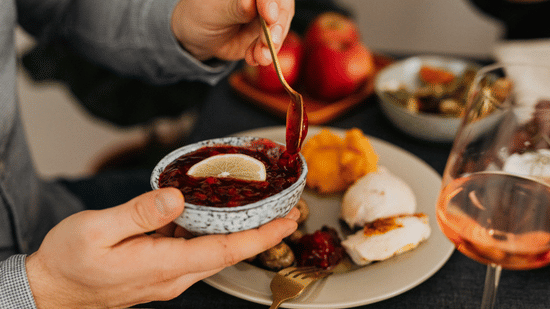 A close-up shot of a person about to scoop off some jam from a bowl topped with a slice of lemon.