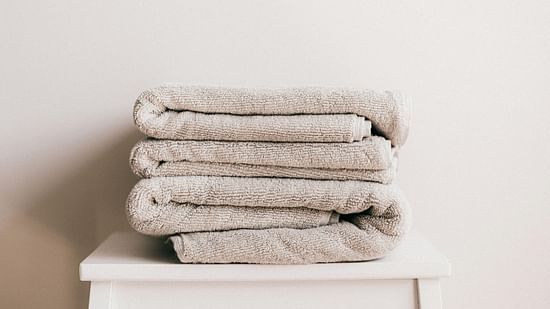 a few white coloured towels neatly folded and kept on a stool