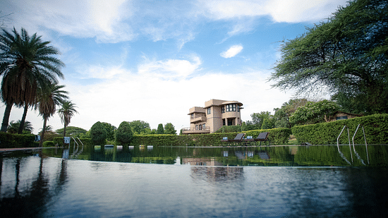 A picturesque view of Clarks Safari, Pushkar as its reflection is shown on water surrounded by greenery