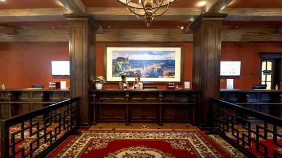 Front view of the front desk at a hotel with a red-patterned carpet covering the floor.