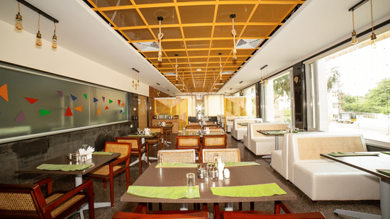 Interior of the restaurant dining room, featuring multiple tables and chairs under a patterned wooden ceiling at Icon Express By Bhagini, Mahadevapura.