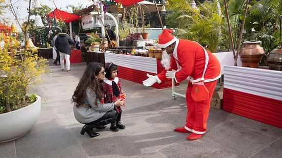 image of a mother holding her child and a man wearing Santa costume at karma lakelands