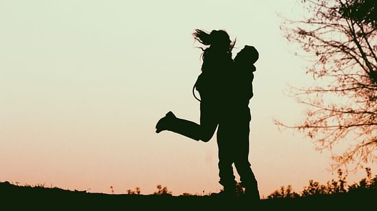 silhouette of a couple during evening standing near a tree
