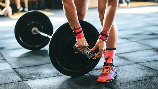 A person adding weights on  the barbell.