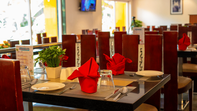 Image of a dining table at restaurant displaying cutlery and a mini vase placed on it