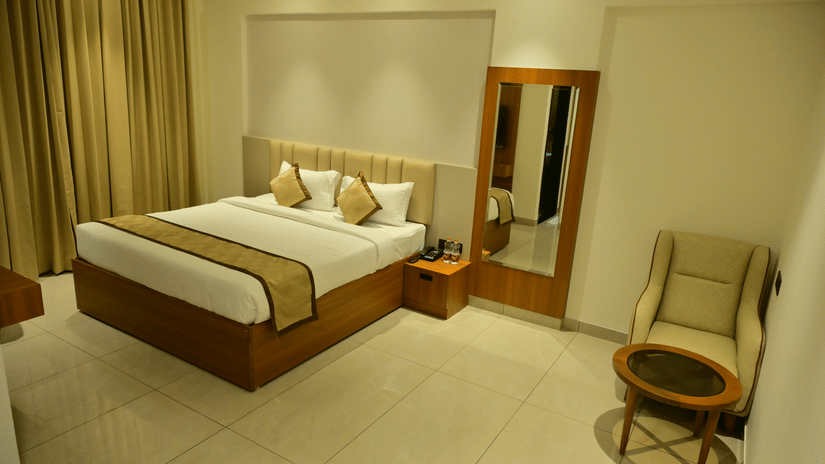 Bedroom of Bhavanis Vista By Icon featuring a bed, a headboard, an armchair, and a mirror.