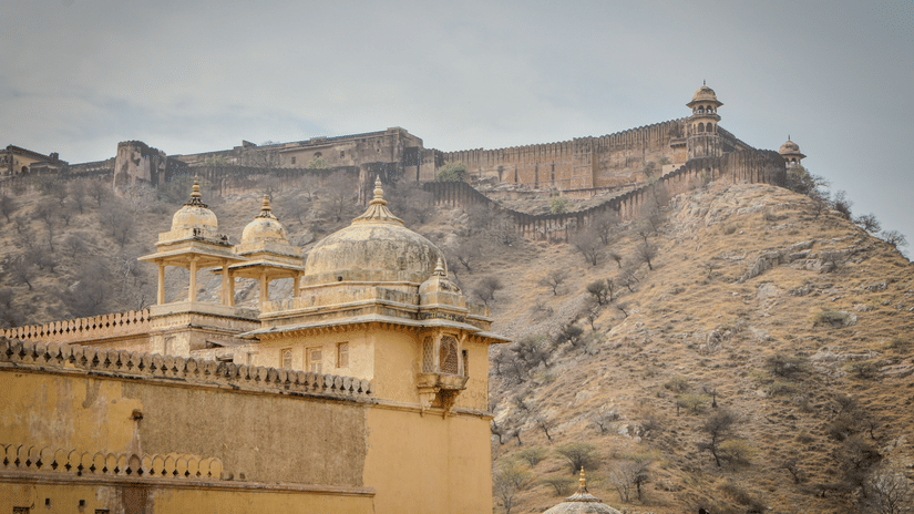 The facade of the Jaigarh Fort perched atop a mountain range with rustic brown walls viewed from Amer Fort in Jaipur.