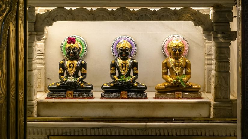 Three statues of Buddha sitting next to each other in a row