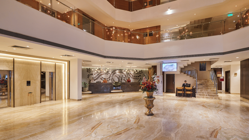 A lobby of The Pride Premier Nagpur featuring a huge space, a decoratiev piece placed at the centre of the lobby, and there are several floors above it.