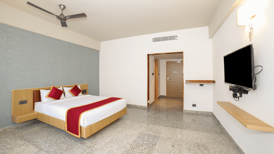 A double bed, a wall-mounted television, and a doorway at Icon Express By Bhagini, Mahadevapura.