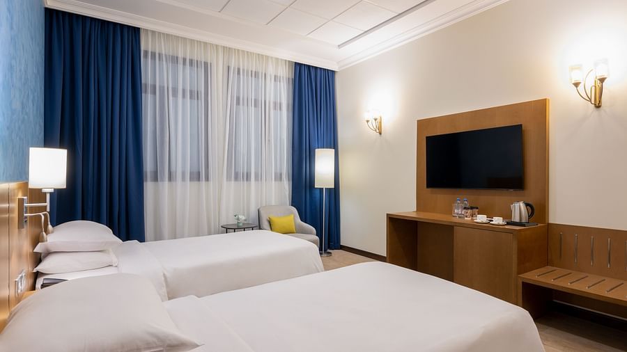 Twin beds in front of a wall mounted TV inside Class Twin Beds - La Maison Hotel, Doha