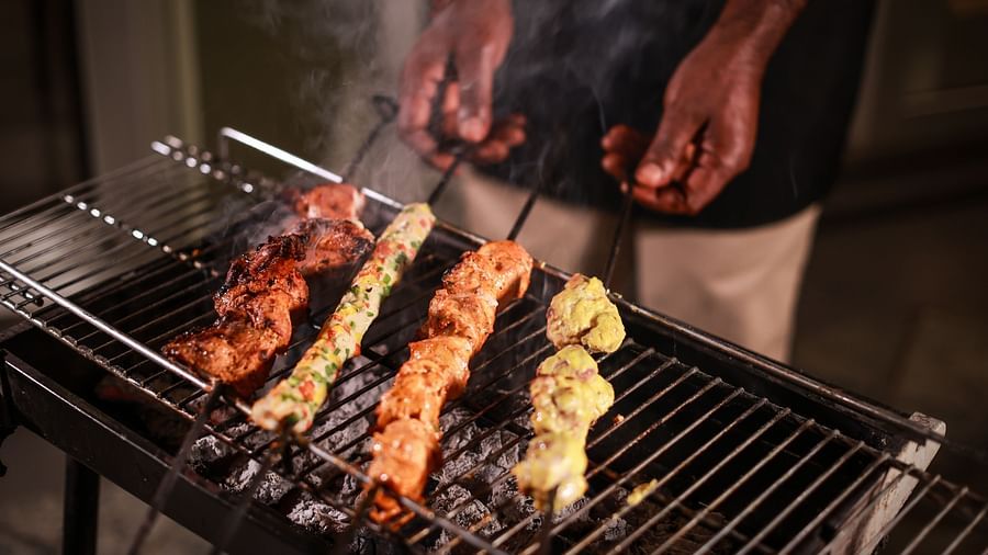 A closer view of a chef holding grilled food on a BBQ pan coated with flavourful spices - Lamrin Norwood Green, Palampur