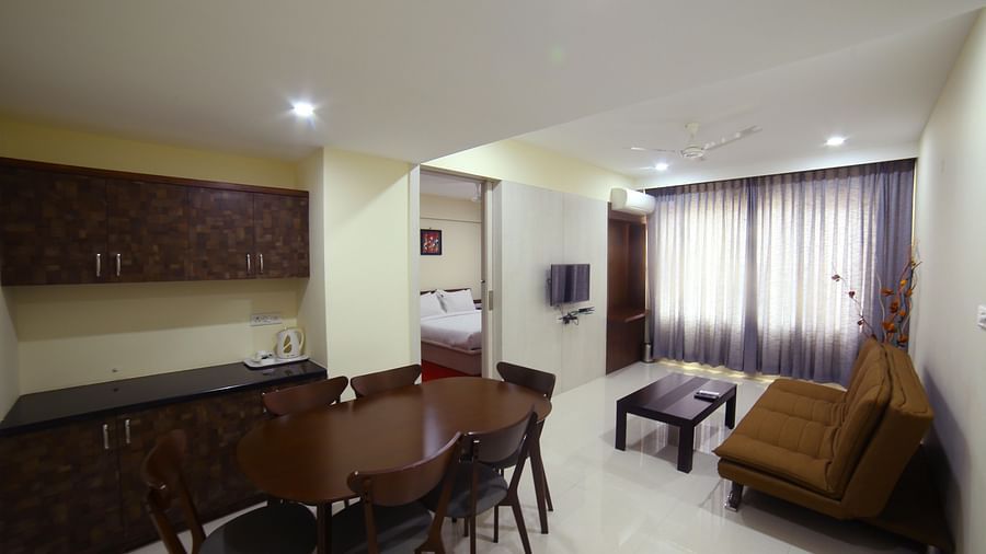 Mysore Gate Hotel, Bangalore Bengaluru A living area featuring a sofa a table kitchen counter and a dining area - Mysore Gate Hotel Bangalore