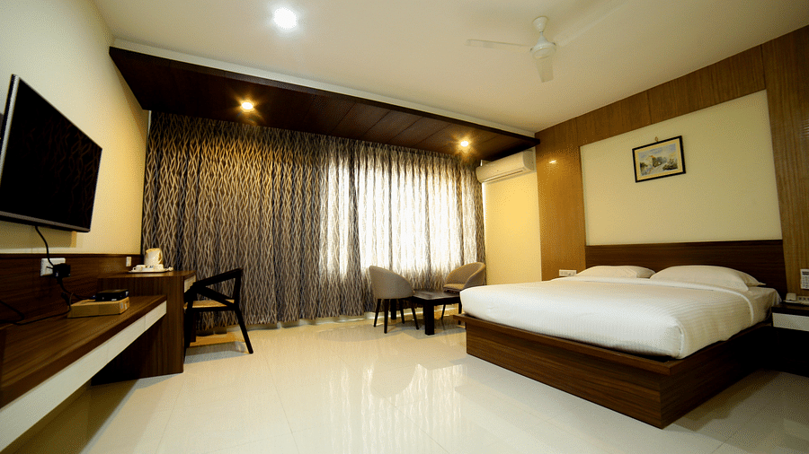 Mysore Gate Hotel, Bangalore Bengaluru A room with neat bed sofa chairs and study desk and a TV - Mysore Gate Hotel Bangalore