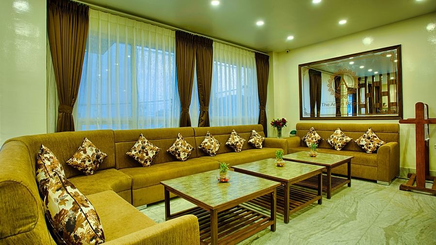 side angle view of lobby area with green-yellow colour furniture and curtained windows behind the couch - the aryan regency
