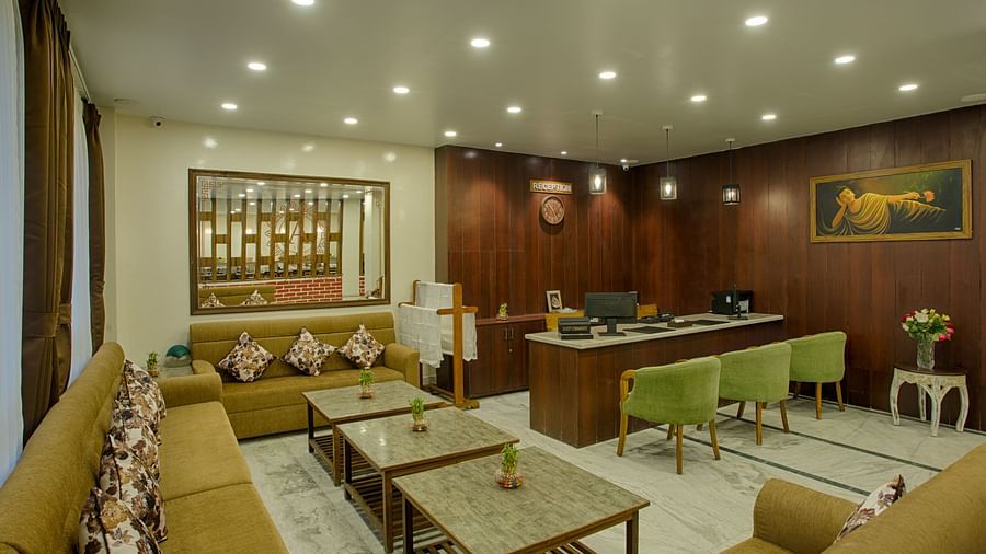 full view of lobby area with green-yellow colour furniture and curtained windows behind the couch - the aryan regency