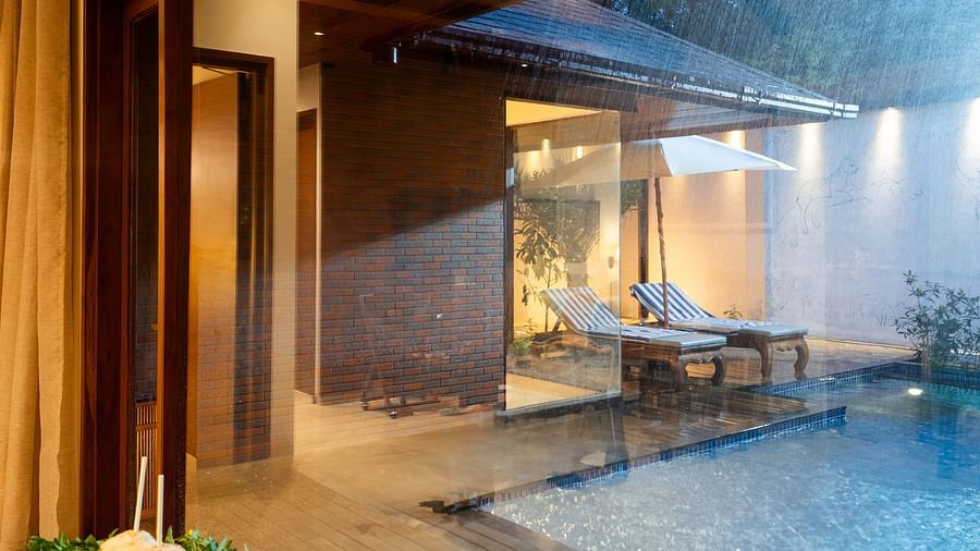 Pool villa at Uday Backwater Resort with a private pool, wooden deck, lounge chairs, and warm ambient lighting during a rainy evening