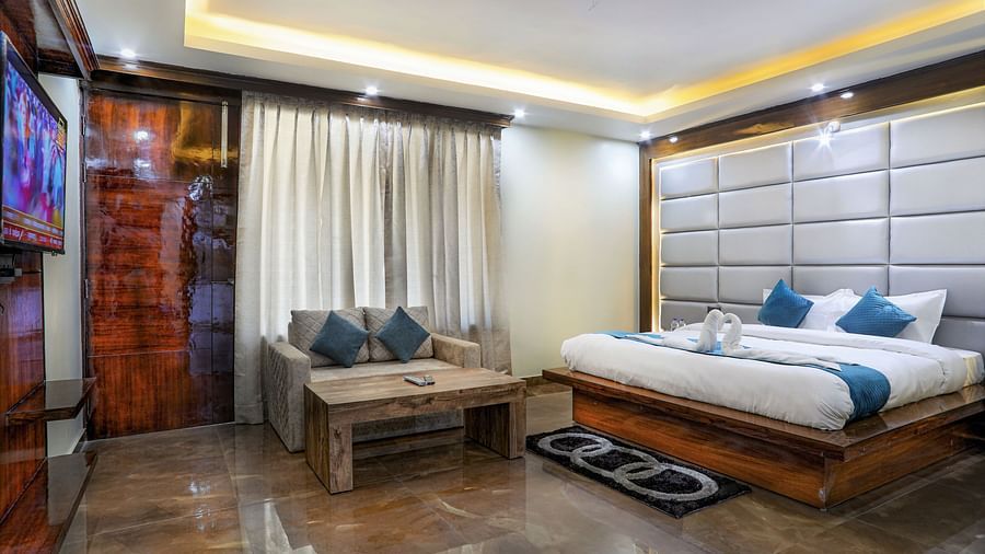 A room with a bed, sofa, coffee table, smart TV, carpet and a wooden door - Vinsober Monal, Nainital
