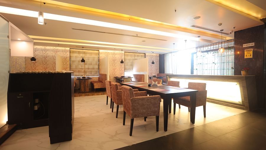 A brightly lit dining area with tables and chairs, soft pink seating, and warm overhead lighting - VITS Gurugram