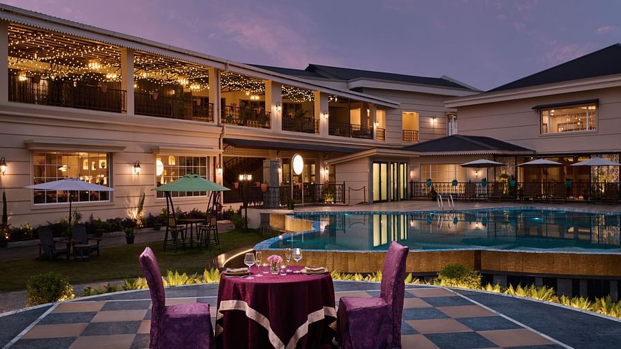 Outdoor swimming pool at Voyage The Solitaire Bliss, set against a stunning sunset sky, with the hotel building beautifully lit by elegant lighting in the background
