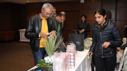 An image of a senor citizen checking out items placed on a table in an exhibition at Heritage Village Resorts & Spa