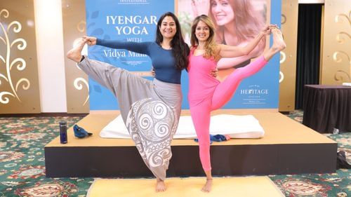 An image of two women stretching their arms and legs to create a yoga pose at Heritage Village Resorts & Spa