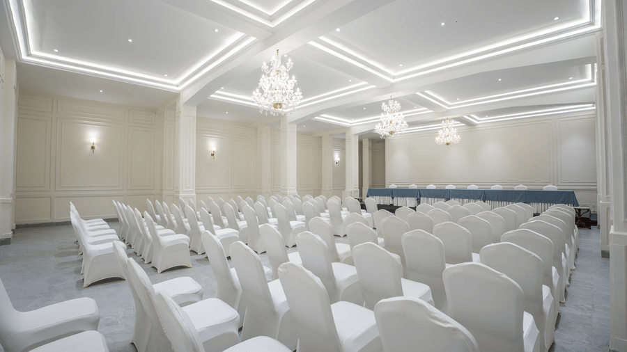 A conference hall with rows of covered chairs facing a stage area under ceiling lights at Summit Norbu Ghang - The Signature Collection, Gangtok.