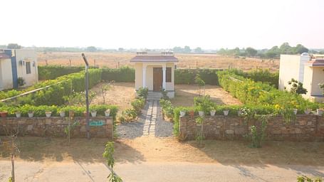Aerial view of the Studio Villa at Aanandam Resort & Spa, showcasing a fenced greenery, and a scenic pathway leading to the villa